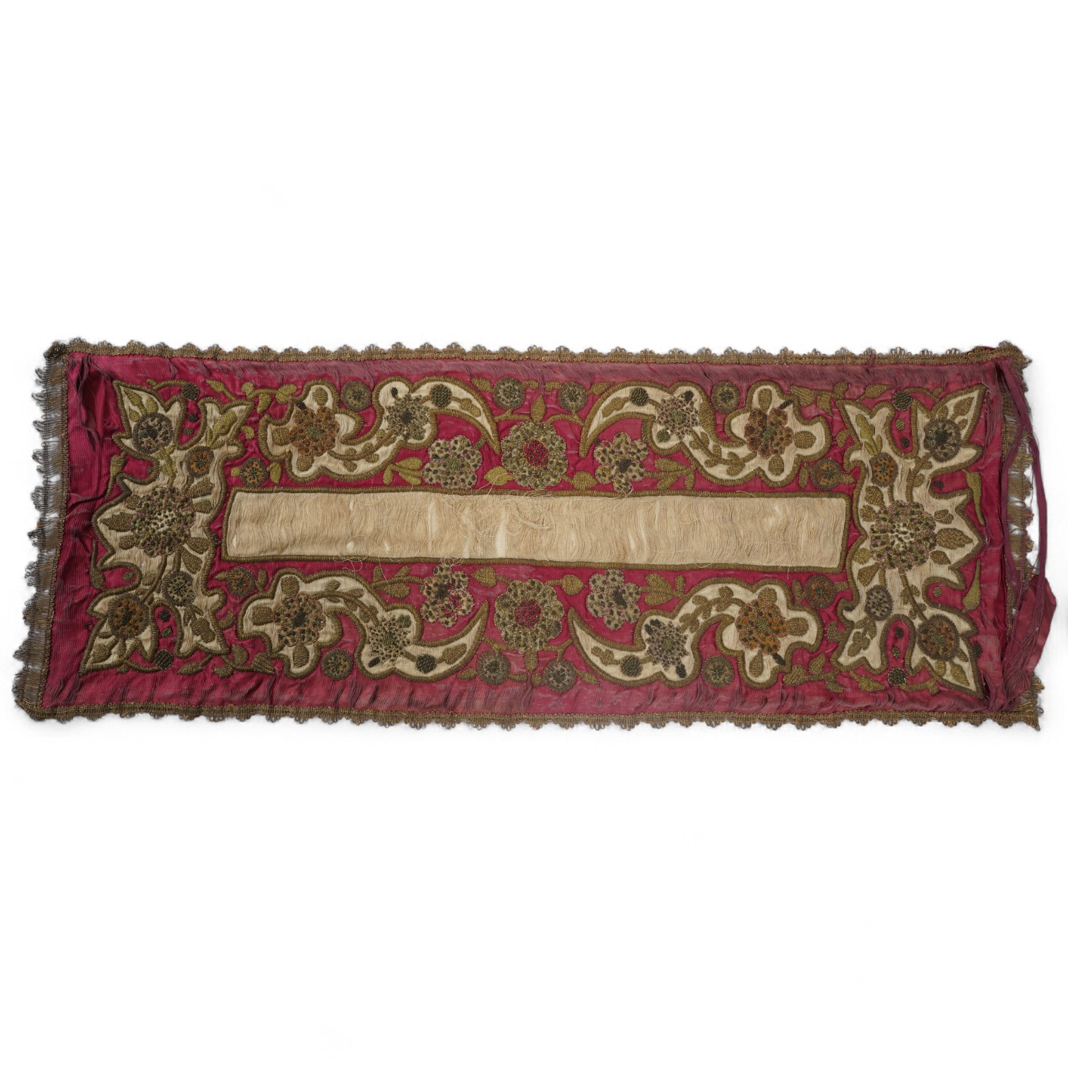 A 19th century Indian red and cream silk runner, heavily embroidered with scrolling motifs, using a variety of stump work and gold wire work stitches, with earlier Mughal influences, 118cm x 46.5cm (not including braid),